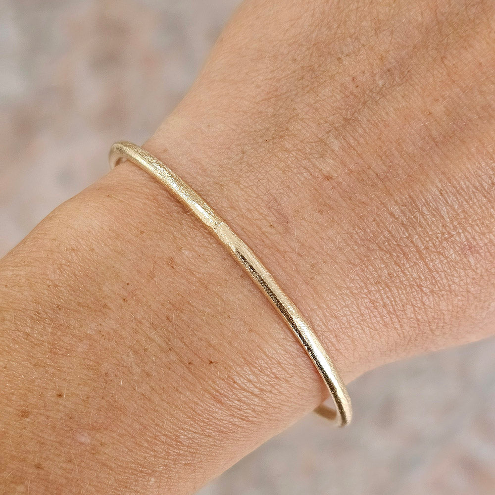sandcast gold bracelet on hand, handmade cuff by zoe alexandria jewellery