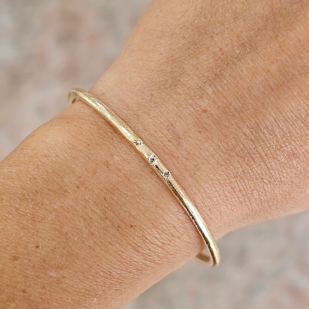 Gold bracelet with three diamond stones, on wrist handmade cuff by zoe alexandria jewellery