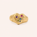 A textured gold ring shaped like a stylized abstract face, featuring small colorful gemstones in purple, pink, blue, green, and dark blue, sandcast signet ring by zoe alexandia jewllery